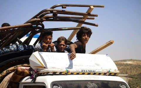 Young boys sit atop a truck as they flee rebel-held areas of the city of Daraa - Credit: MOHAMAD ABAZEED/AFP/Getty Images