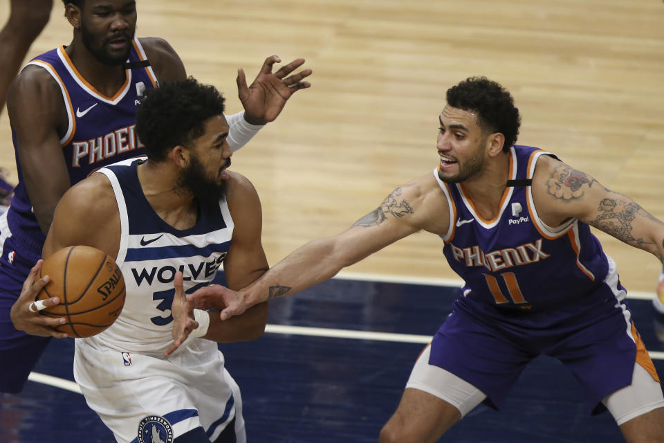 Minnesota Timberwolves's Karl-Anthony Towns (32) tries to maintain control of the ball against Phoenix Suns' Abdel Nader (11) in the first half of an NBA basketball game Sunday, Feb. 28, 2021, in Minneapolis. (AP Photo/Stacy Bengs)