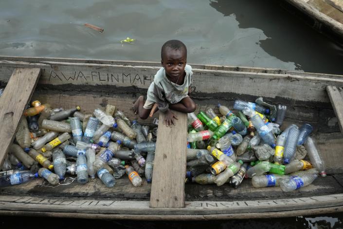 FILE - A child sits inside a canoe with empty plastic bottles he collected to sell for recycling in the floating slum of Makoko in Lagos, Nigeria, Nov. 8, 2022. More than 2,000 experts plan to wrap up early negotiations Friday, Dec. 2, on plastic pollution at one of the largest global gatherings ever to address the crisis. (AP Photo/Sunday Alamba, File)