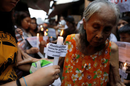 Protesters and residents hold lighted candles at the wake of Kian Loyd delos Santos, a 17-year-old high school student, who was among the people shot dead last week in an escalation of President Rodrigo Duterte's war on drugs in Caloocan city, Metro Manila, Philippines August 21, 2017. REUTERS/Erik De Castro