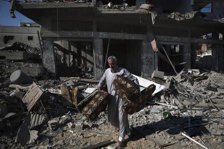 A Palestinian man salvages belongings from damaged buildings in the Shejaia neighbourhood, which witnesses said was heavily hit by Israeli shelling and air strikes during an Israeli offensive, in Gaza City July 27, 2014. REUTERS/Finbarr O'Reilly