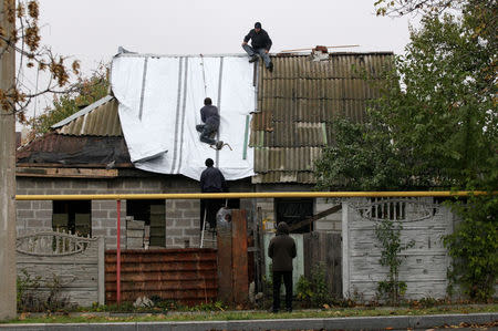 People fix the roof of a house, damaged in fighting between Ukrainian troops and rebels, in the Oktyabrsky district of Donetsk, Ukraine, October 25, 2017. REUTERS/Alexander Ermochenko