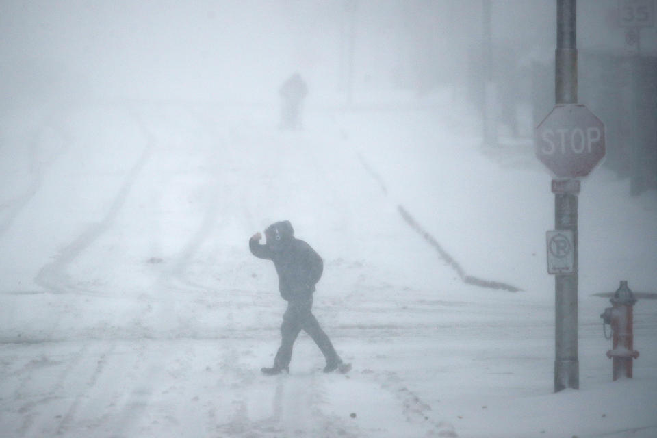 Pedestrians walk as snow falls Sunday, Nov. 25, 2018, in Kansas City, Mo. Blizzard-like conditions have closed highways and delayed air travel as a winter storm moves through the Midwest. (AP Photo/Charlie Riedel)