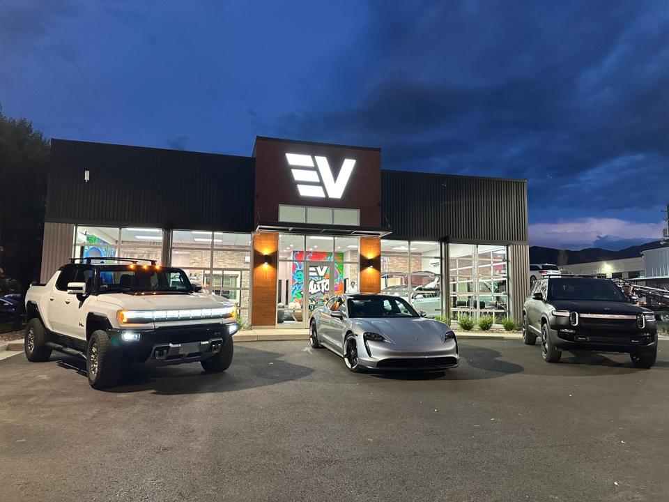 Three EVs are parked in front of an EV dealership.