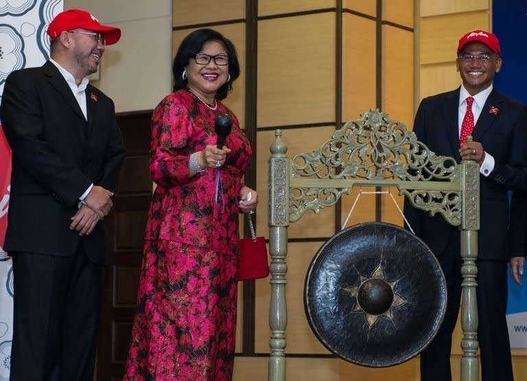 Independent non-executive chairman of AirAsia X Rafidah Aziz (C) prepares to hit a gong to mark the firm's listing debut alongside CEO Azran Osman-Rani (R) and director Kamarudin Meranun at the stock exchange in Kuala Lumpur on July 10, 2013. Shares in the long-haul budget carrier ended flat on their market debut, despite Osman-Rani promising a spending spree on new planes