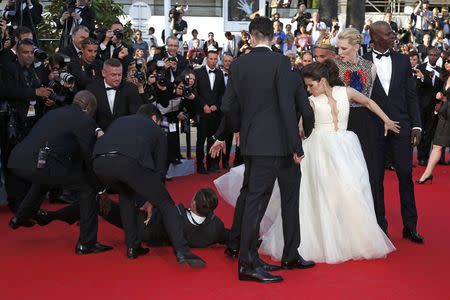 A man is arrested by security as he tries to slip under the dress of actress America Ferrera (3rdR) as she poses on the red carpet arriving for the screening of the film "How to Train Your Dragon 2" out of competition at the 67th Cannes Film Festival in Cannes May 16, 2014. REUTERS/Benoit Tessier