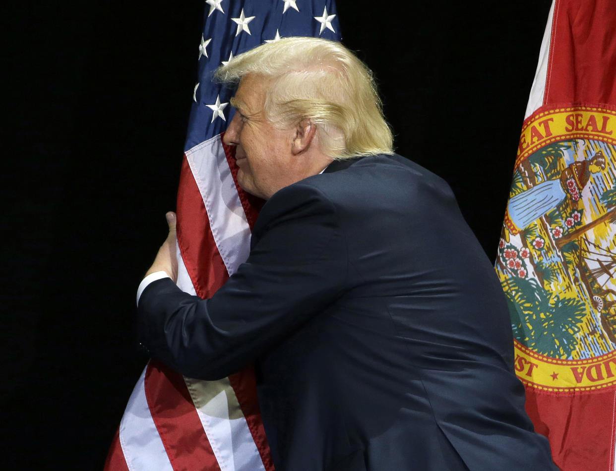 Donald Trump pauses during his campaign speech to hug the American flag on June 11, 2016, in Tampa, Fla. (Photo: Chris O'Meara/AP)