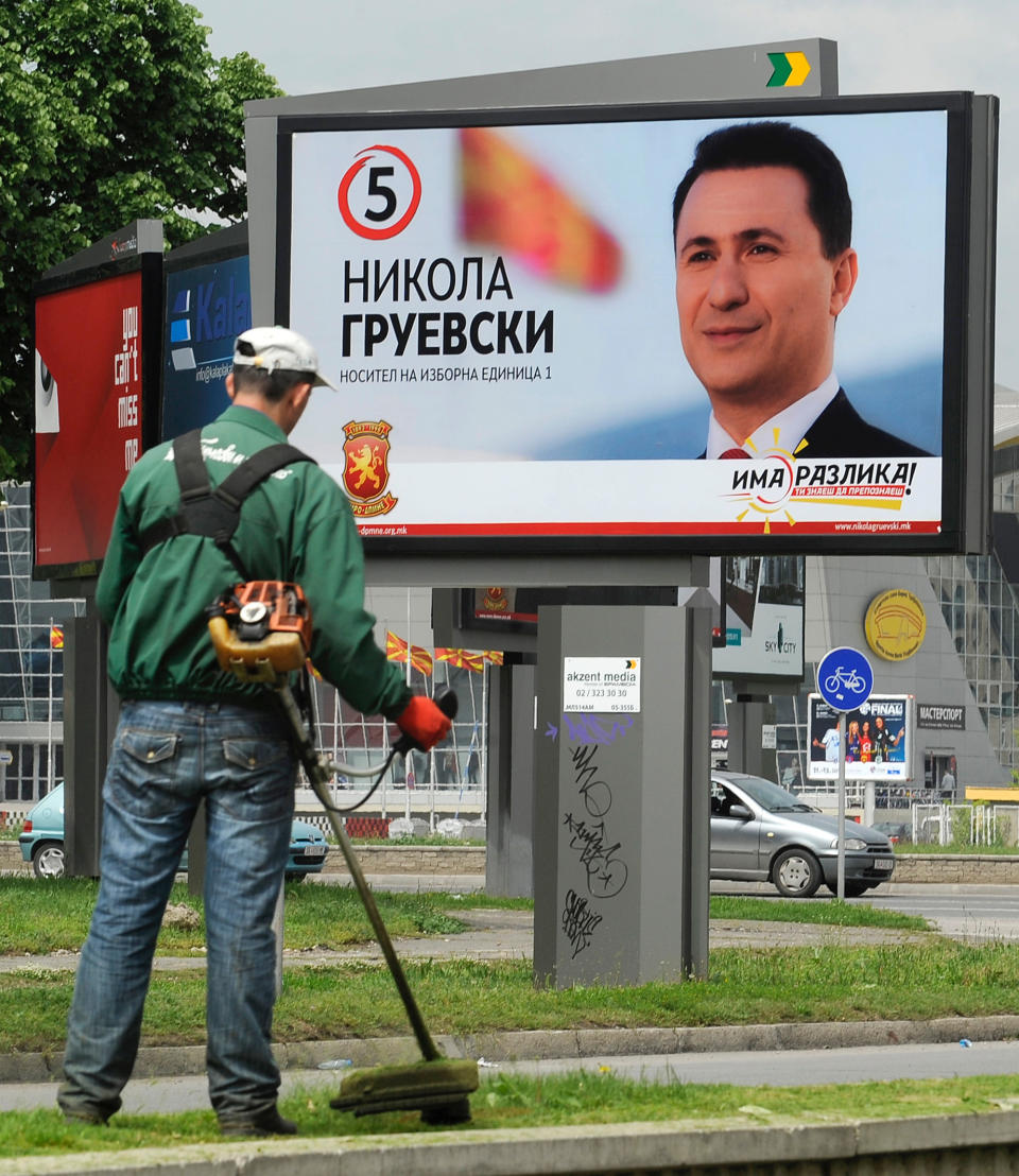 In this photo taken Thursday, April 24, 2014, a worker cuts grass near a board with an electoral poster of Macedonian Prime Minister and leader of the ruling conservative VMRO-DPMNE party Nikola Gruevski, reading "There is a difference - You know how to recognize it", in Macedonia's capital Skopje. Macedonia’s ruling conservatives are vying to cement their dominance in twin elections for prime minister and president Sunday, gambling on the success of their economic program despite high unemployment and failure to resolve a dispute with neighbor Greece that kept the tiny country from joining NATO entry and achieving closer ties with the European Union. (AP Photo/Boris Grdanoski)