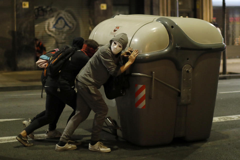 Protestors push garbage containers to build a barricade across a street in Barcelona, Spain, Thursday, Oct. 17, 2019. Catalonia's separatist leader vowed Thursday to hold a new vote to secede from Spain in less than two years as the embattled northeastern region grapples with a wave of violence that has tarnished a movement proud of its peaceful activism. (AP Photo/Emilio Morenatti)