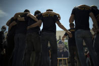 Police officers console each other during a ceremony to commemorate a slain colleague at a police station in Avignon, southern France, Sunday, May 9, 2021. Police officers and civilians gathered to commemorate the death of a police officer who was killed Wednesday at a known drug-dealing site in the southern France city of Avignon. (AP Photo/Daniel Cole)