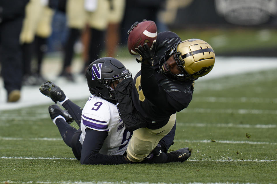 Purdue wide receiver TJ Sheffield (8) reaches for yardages as he's tackled by Northwestern defensive back Jeremiah Lewis (9) during the first half of an NCAA college football game in West Lafayette, Ind., Saturday, Nov. 19, 2022. (AP Photo/Michael Conroy)