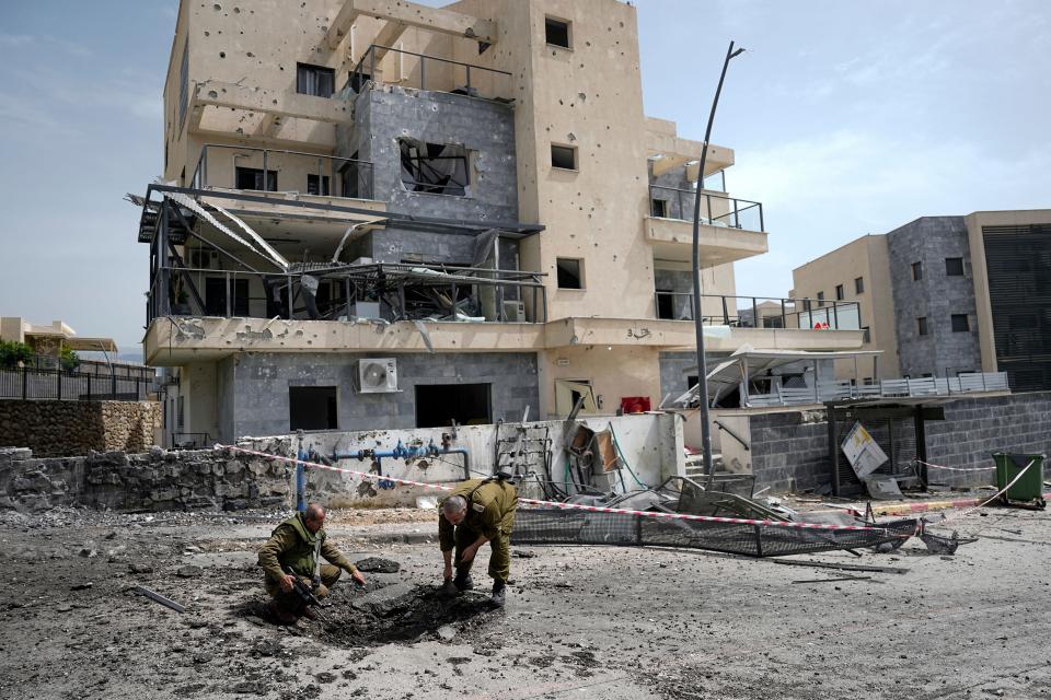 Israeli security forces examine the site hit by a rocket fired from Lebanon in Kiryat Shmona, northern Israel, on March 27.