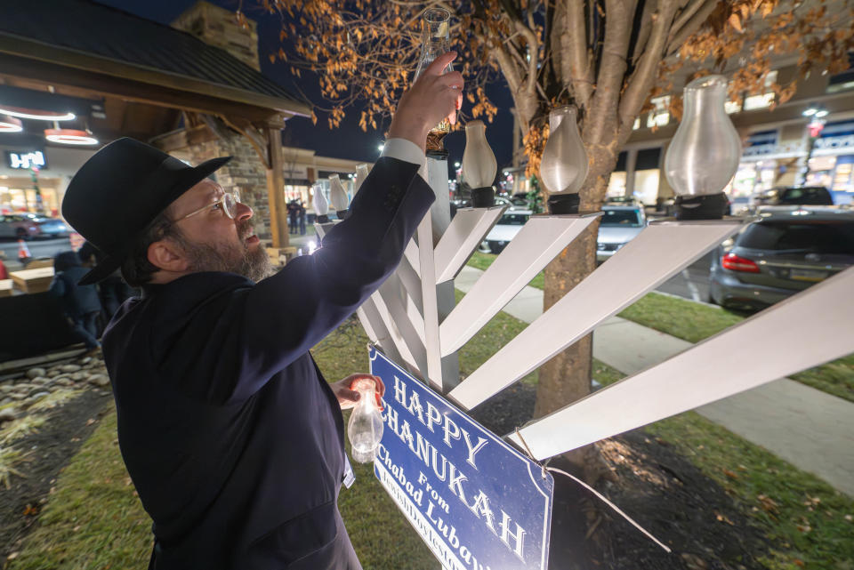 Rabbi Mendel, of Chabad Lubavitch of Doylestown, leads the Hanukkah celebration with the menorah lighting at the Shops of Valley Square in Warrington on Thursday night. Festivities featured songs, a bubble show, a gelt drop and traditional treats.