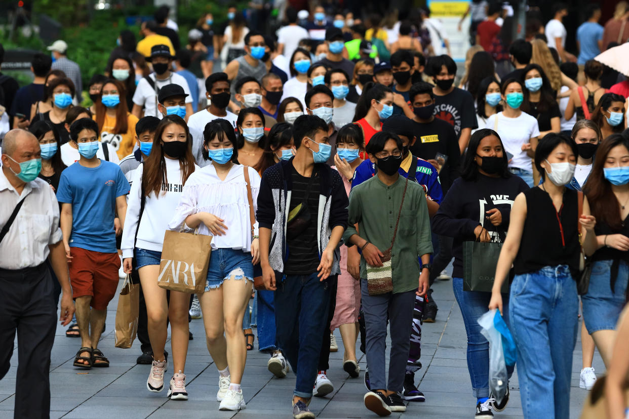 SINGAPORE - JUNE 20:  People wearing protective masks walk along Orchard Road shopping belt on June 20, 2020 in Singapore. From June 19, Singapore started to further ease the coronavirus (COVID-19) restrictions by allowing social gatherings up to five people, re-opening of retail outlets and dining in at food and beverage outlets, subjected to safe distancing. Parks, beaches, sports amenities and public facilities in the housing estates will also reopen. However, large scale events, religious congregations, libraries, galleries and theatres will remain closed.  (Photo by Suhaimi Abdullah/Getty Images)