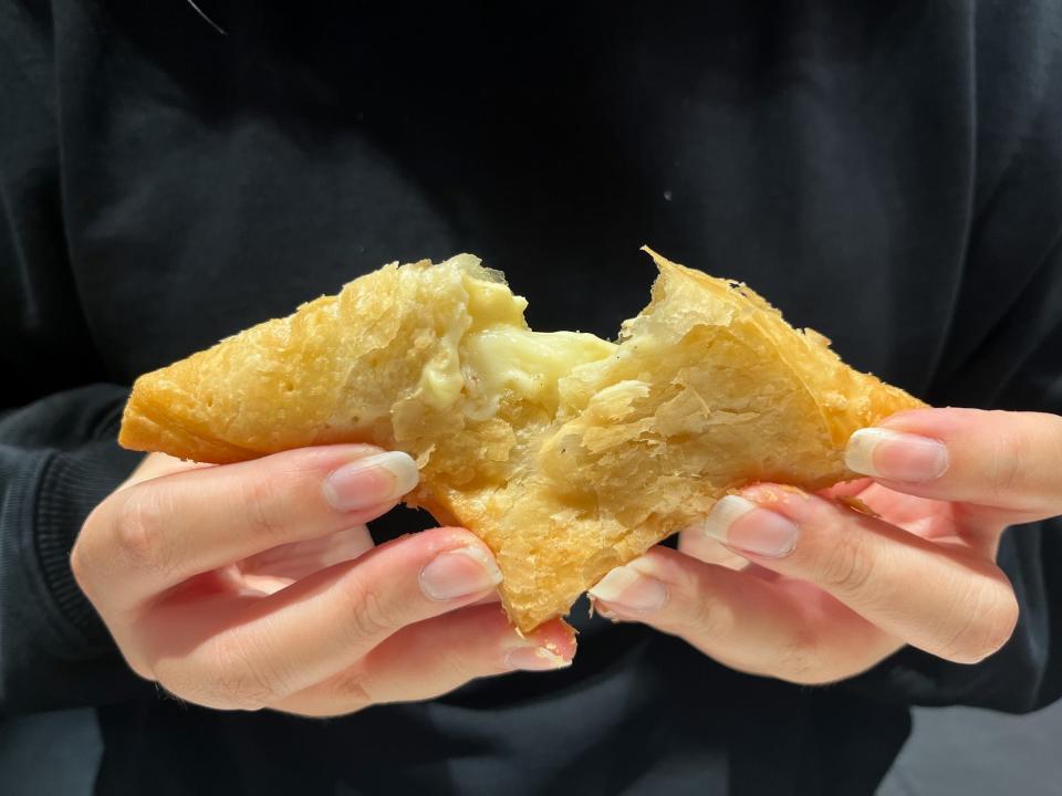 A flaky pie pastry being split apart and held in two hands.