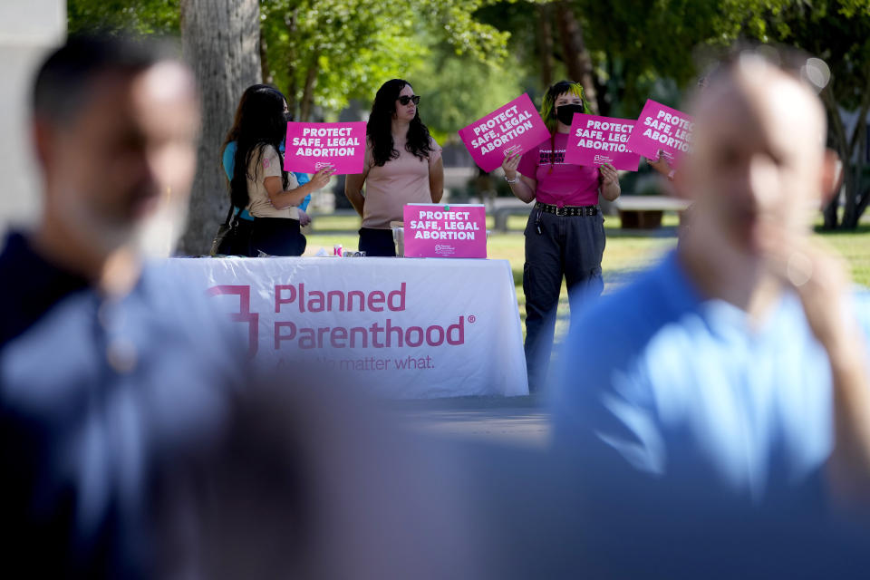 Anti-abortion supporters kneel as abortion supporters holds signs in the background, Wednesday, May 1, 2024, at the Capitol in Phoenix. Democrats secured enough votes in the Arizona Senate to repeal a Civil War-era ban on abortions that the state's highest court recently allowed to take effect. (AP Photo/Matt York)