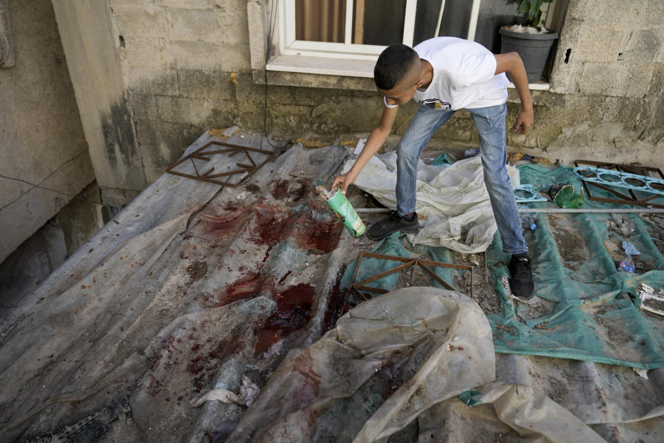 A boy looks at blood stains after a military raid in the Nur Shams refugee camp near the city of Tulkarem, in the occupied West Bank Saturday, May 6, 2023. Israeli forces shot dead two Palestinians during a military raid in the occupied West Bank Saturday, the Palestinian Health Ministry said, while a local armed group said the pair were militants.The ministry and Tulkarem's branch of Al Aqsa Martyrs Brigades, a militant group with connections to President Mahmoud Abbas' Fatah party, identified the pair as Samer El Shafei and Hamza Kharyoush, both aged 22 years. (AP Photo/Majdi Mohammed)