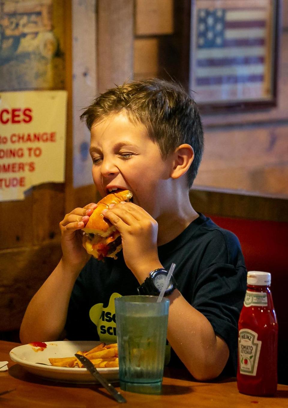 Luca Vidal, de siete años, da un mordisco a la hamburguesa con queso que pidió en el restaurante Wagons West el 1º de julio de 2022, en Pinecrest.
