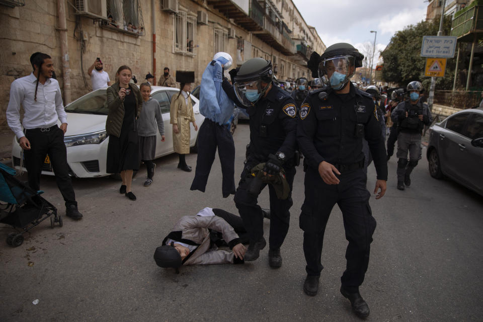 Ultra-Orthodox Jews some wearing costumes scuffle with police officers during celebrations of the Jewish holiday of Purim, in the Mea Shearim ultra-Orthodox neighborhood of Jerusalem, Sunday, Feb. 28, 2021. The Jewish holiday of Purim commemorates the Jews' salvation from genocide in ancient Persia, as recounted in the biblical Book of Esther. (AP Photo/Oded Balilty)