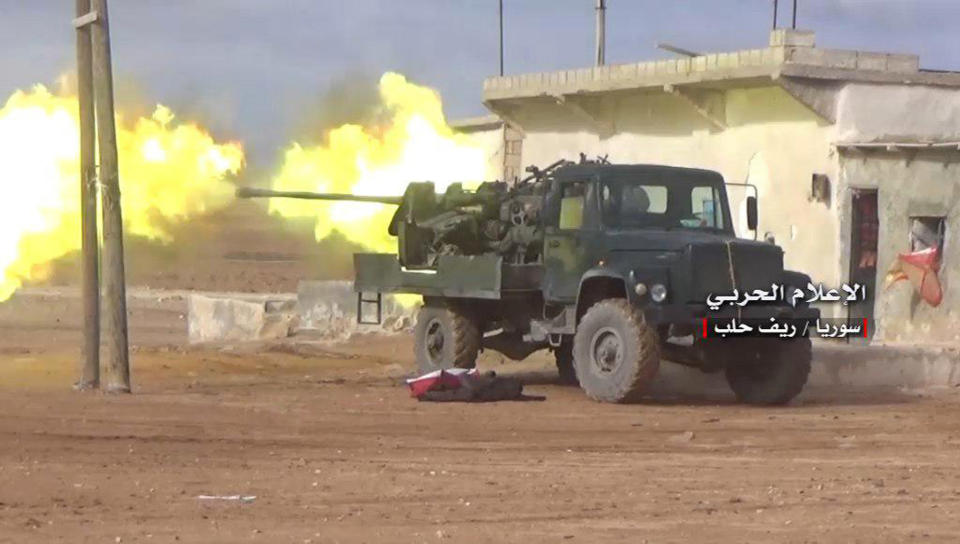 FILE -- In this Saturday, Jan. 20, 2018 file photo, provided by the government-controlled Syrian Central Military Media, shows Syrian government forces firing their weapon during a battle against the Syrian opposition fighters, in the southern Aleppo countryside, Syria. In two months of intensive airstrikes and bombardments on the rebel-controlled province of Idlib, Syrian government forces and their Russian allies have failed to make progress against battle-hardened insurgents. (Syrian Central Military Media, via AP, File)