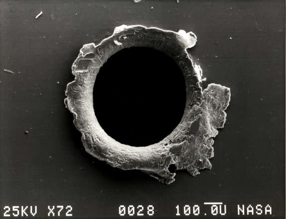 An image a tiny puncture made by orbital debris, or space junk, on the Solar Maximum Mission satellite.