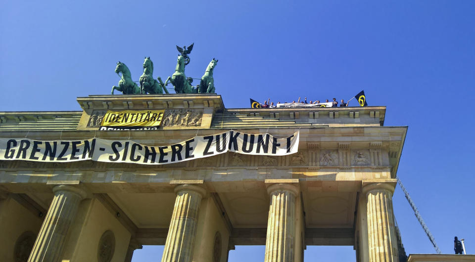 Activists of the Identitarian Movement protest on the Brandenburg Gate with a banner reading 'secure borders - secure fututre'Saturday, Aug. 27, 2016.The German domestic intelligence agency says it is stepping up observation of the far-right Identitarian Movement in Germany that campaigns against immigrants and Islam. (AP Photo/Frank Jordans)