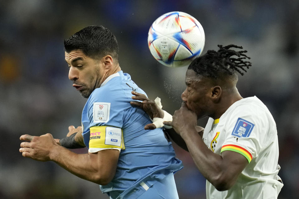 El ghanés Mohammed Salisu (derecha) salta por un balón con el uruguayo Luis Suárez durante un partido del Grupo H del Mundial que enfrentó a ambas selecciones en el estadio Al Janoub en Al Wakrah, Qatar, el 2 de diciembre de 2022. (AP Foto/Ashley Landis)