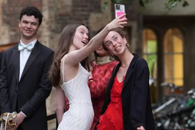Two girls taking a selfie. One in a white dress and one dressed in red