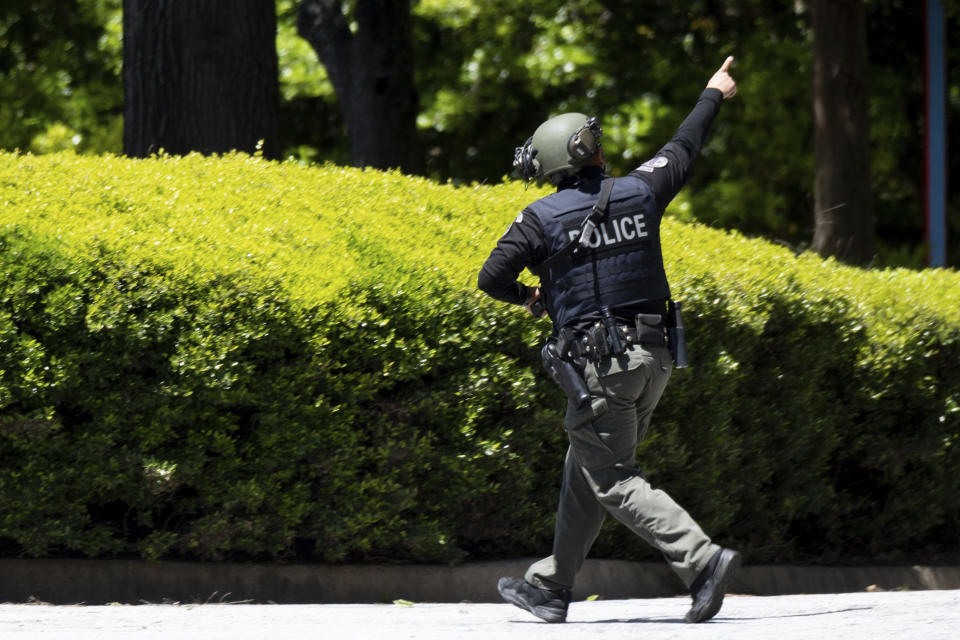 A police officer runs while pointing to a roof after a shooting in Atlanta on Wednesday, May 3, 2023. (AP Photo/Ben Gray)