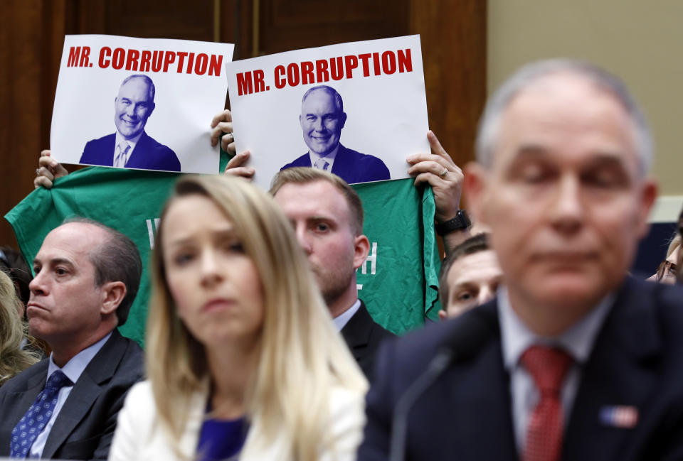 Protestors hold up signs and message T-shirts behind EPA chief Scott Pruitt, and Holly Greaves, EPA chief financial officer, as they testify at a hearing of the House Energy and Commerce subcommittee. (AP Photo/Alex Brandon)