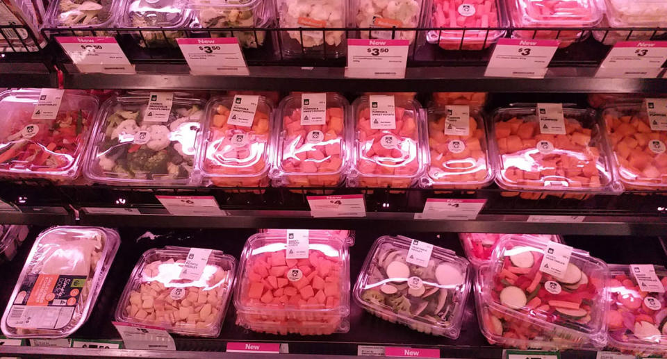 A Woolworths supermarket shelf with pumpkin, broccoli, cauliflower and other vegetables. They are in plastic containers.