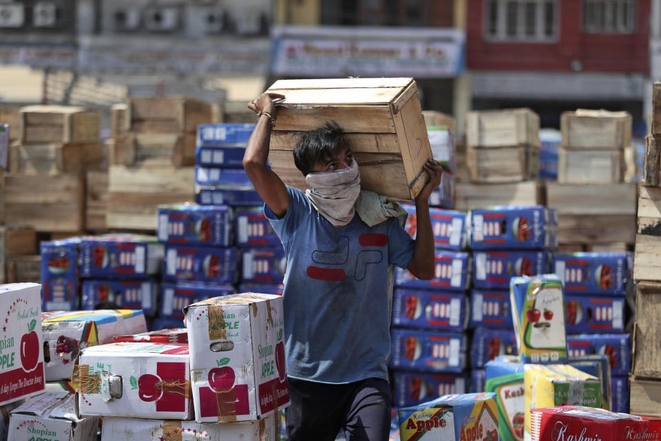 An Indian laborer wearing a mask carries boxes of apples at a wholesale market on the outskirts of Jammu, India, Wednesday, Sept.23, 2020. The nation of 1.3 billion people is expected to become the pandemic's worst-hit country within weeks, surpassing the United States. (AP Photo/Channi Anand)