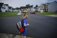 FILE - In this Aug. 3, 2020, file photo, Paul Adamus, 7, waits at the bus stop for the first day of school in Dallas, Ga. As schools reopen around the country, their ability to quickly identify and contain coronavirus outbreaks before they get out of hand is about to be put to the test. (AP Photo/Brynn Anderson, File)