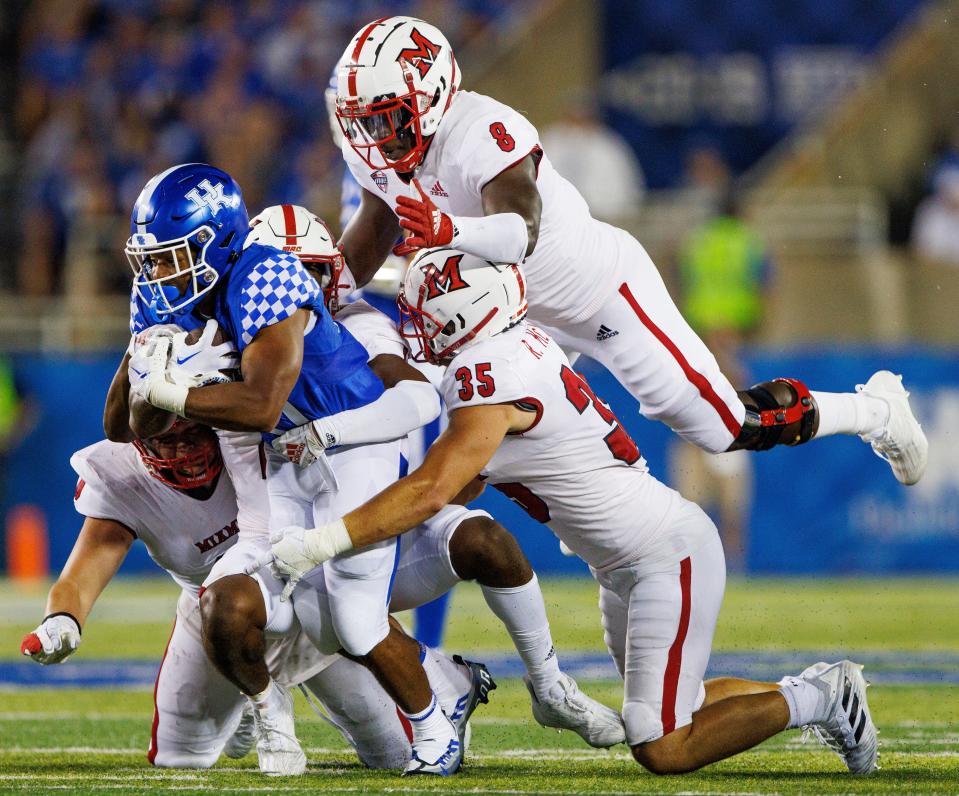 Kentucky running back JuTahn McClain, front left, is tackled by Miami (Ohio) linebacker Ryan McWood (35), defensive lineman Brian Ugwu (8), defensive lineman Austin Ertl, bottom left, and defensive back Eli Blakey, center, during the second half of an NCAA college football game in Lexington, Ky., Saturday, Sept. 3, 2022. (AP Photo/Michael Clubb)