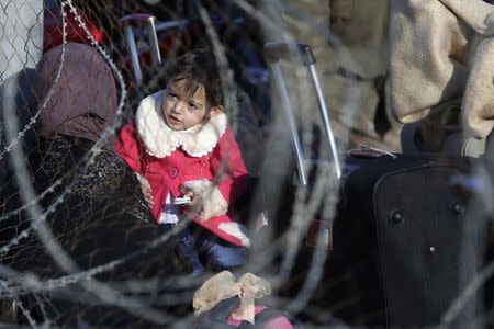 A Palestinian girl, hoping to cross into Egypt with her mother, is pictured through a fence as she waits at the Rafah crossing between Egypt and the southern Gaza Strip December 21, 2014. REUTERS/Ibraheem Abu Mustafa