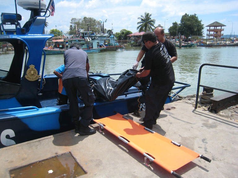 Malaysian officials remove a body from their rescue vessel in Tanjung Sedili, on August 4, 2013