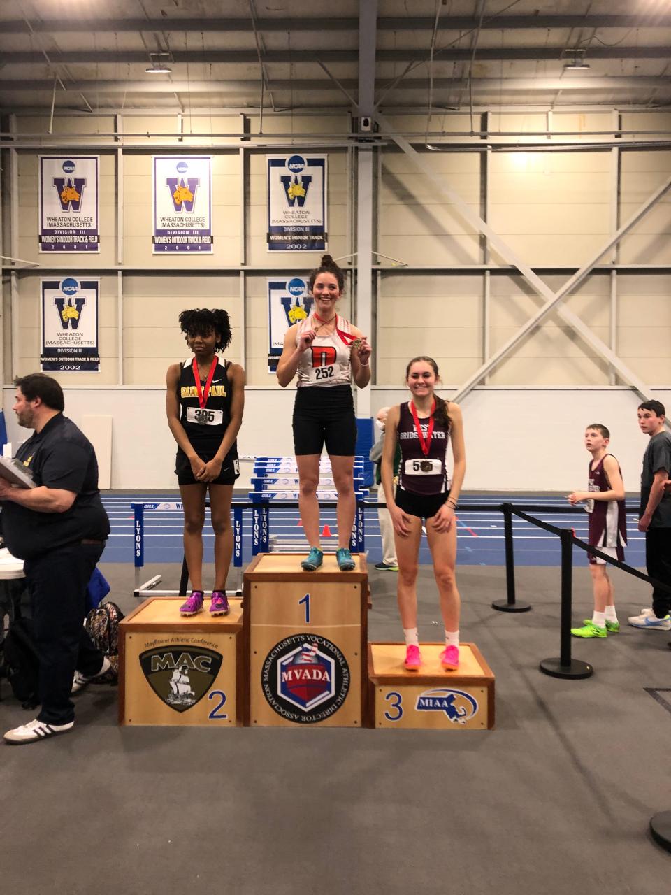 Diman's Inez Medeiros, middle, stands with her first place medal from the Mayflower Athletic Conference championship meet at Wheaton College