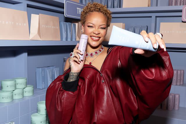 <p>Kevin Mazur/Getty</p> Rihanna poses with Fenty Hair products at the brand's launch party