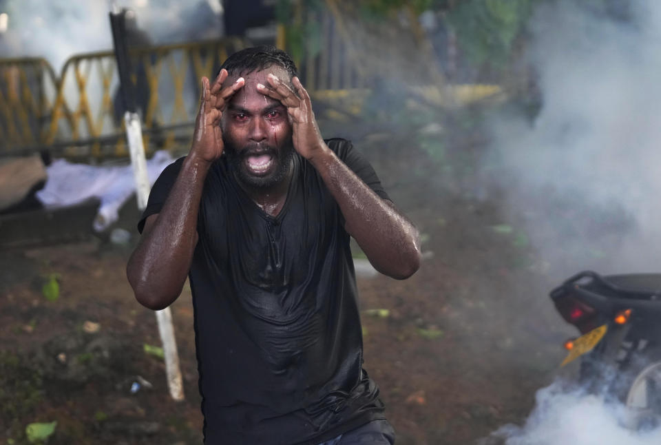 An injured protestor grieves in pain as police fire tear gas to disperse protesting members of the Inter University Students Federation during an anti government protest in Colombo, Sri Lanka, Thursday, May 19, 2022. Sri Lankans have been protesting for more than a month demanding the resignation of President Gotabaya Rajapaksa, holding him responsible for the country's worst economic crisis in recent memory. (AP Photo/Eranga Jayawardena)