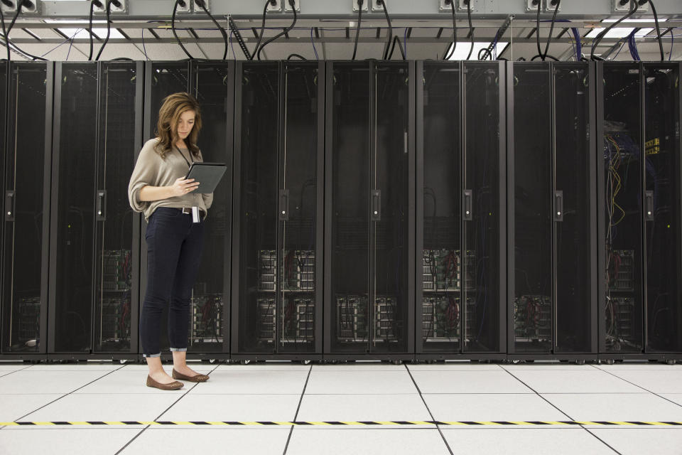 Mixed race businesswoman using tablet computer in server room