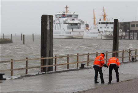 Two workers control a newly built street at the North Sea beach near the town of Norddeich, December 5, 2013. REUTERS/Ina Fassbender