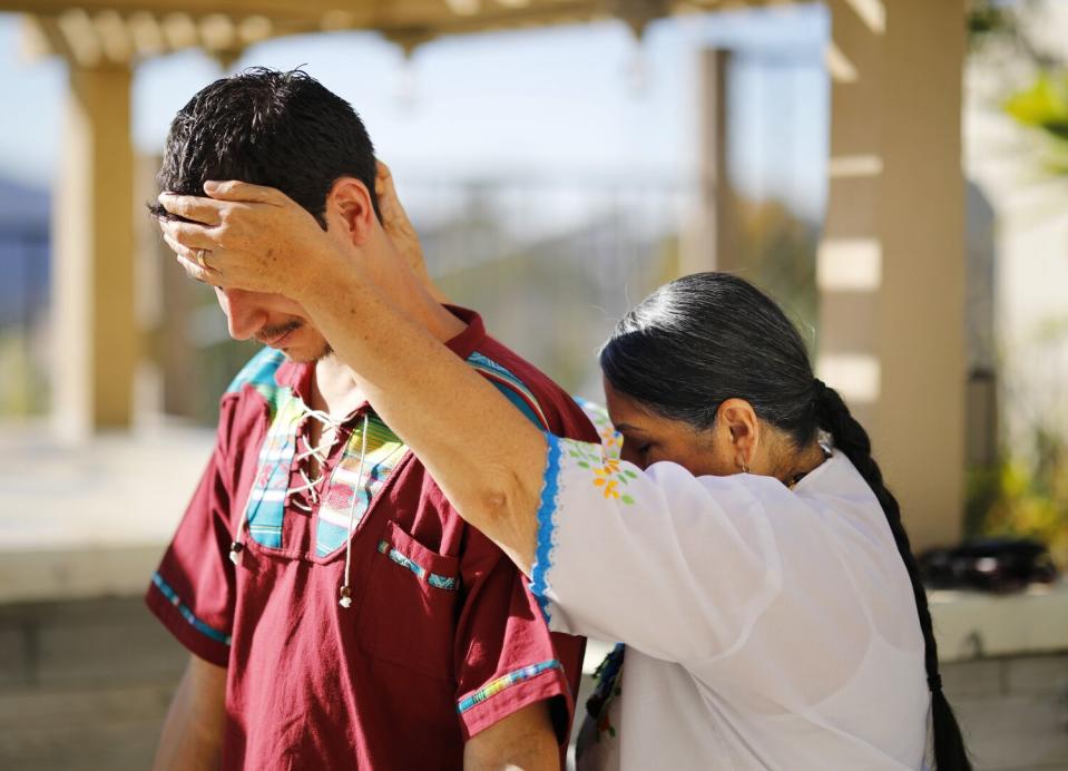 A woman places her hands on a man's forehead and the back of his neck.