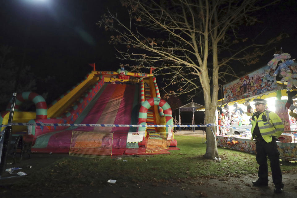 A police officer stands near an inflatable slide at a fireworks funfair in Woking Park, south England, Saturday Nov. 3, 2018. British police say seven of the eight children hurt when they fell from an inflatable slide at a fair in southern England have been discharged from the hospital. (Andrew Matthews/PA via AP)