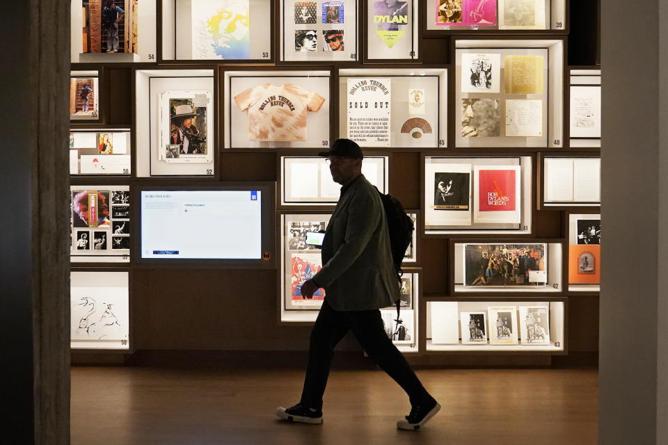 Un hombre pasa frente a una pared con objetos históricos en el Centro Bob Dylan el jueves 5 de mayo de 2022 en Tulsa, Oklahoma. El centro y archivo ofrece una experiencia inmersiva, especio para presentaciones en vivo y alberga miles de objetos que pertenecieron a Dylan. (Foto AP/Sue Ogrocki)