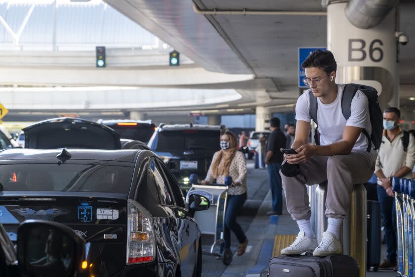 LOS ANGELES, CA - NOVEMBER 28: Arriving home after traveling to Spain Teagan Jarvis, 21, waits for his transportation at Los Angeles International Airport on Sunday, Nov. 28, 2021 in Los Angeles, CA. Sunday after Thanksgiving is one of the busiest days of the year at LAX. (Francine Orr / Los Angeles Times)