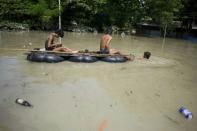 Flood-affected residents use a make-shift raft to travel through floodwaters in Kalay, upper Myanmar's Sagaing region on August 3, 2015