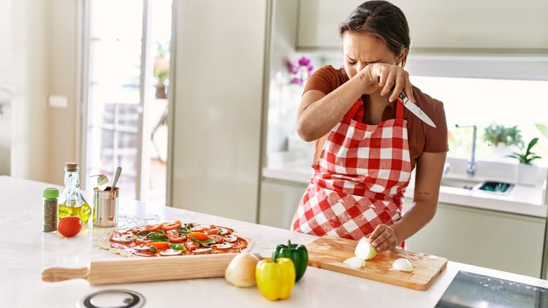 woman crying while cutting onions