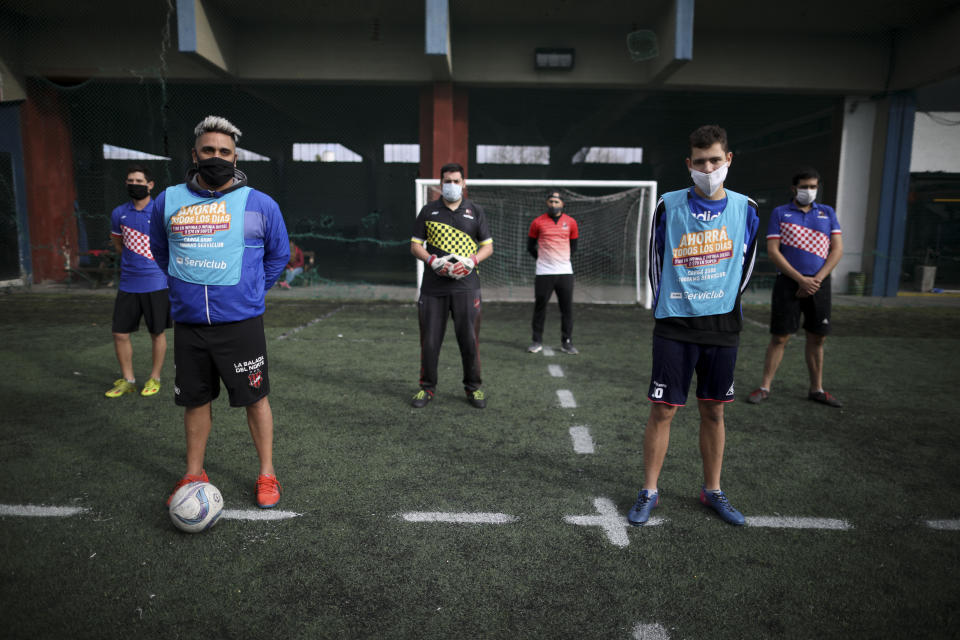 Amateur players stand ahead of a soccer match at the Play Futbol 5 local club in Pergamino, Argentina, Wednesday, July 1, 2020. In order to continue playing amid government restrictions to curb the spread of the new coronavirus, the club divided its soccer field into 12 rectangles to mark limited areas for each player, keeping them from making physical contact. (AP Photo/Natacha Pisarenko)