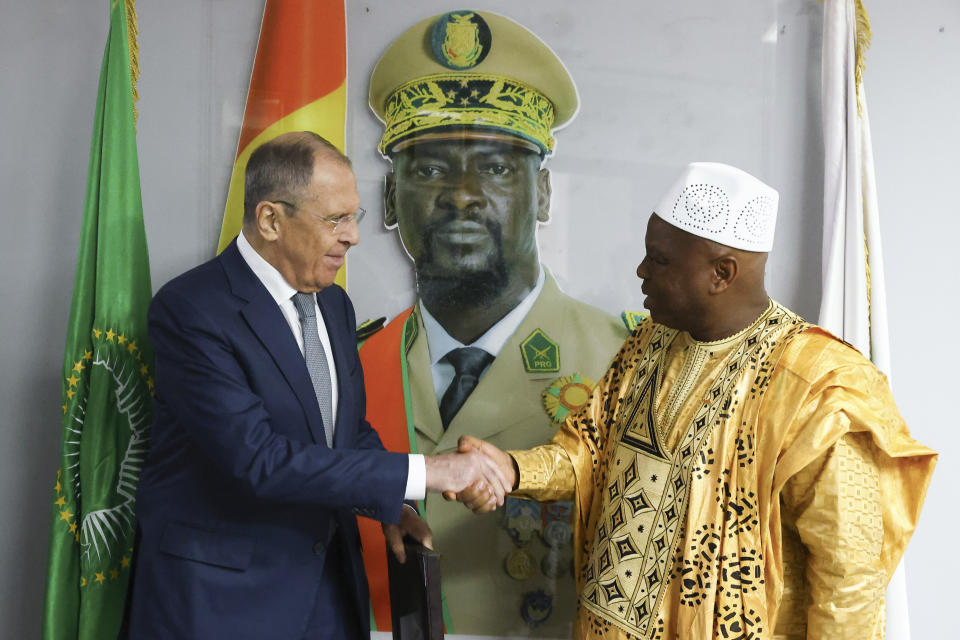 In this photo released by Russian Foreign Ministry Press Service, Russian Foreign Minister Sergey Lavrov, left, and Guinea's foreign minister Morissanda Kouyate shake hands near a portrait of Guinea's President Mamadi Doumbouya during their meeting in Conakry, Guinea, Monday, June 3, 2024. Russian Foreign Minister Sergey Lavrov arrived Monday in Guinea on his latest visit to West Africa, where coups and growing discontent with traditional allies like France and the United States have contributed to some countries' shift towards Moscow. (Russian Foreign Ministry Press Service via AP)