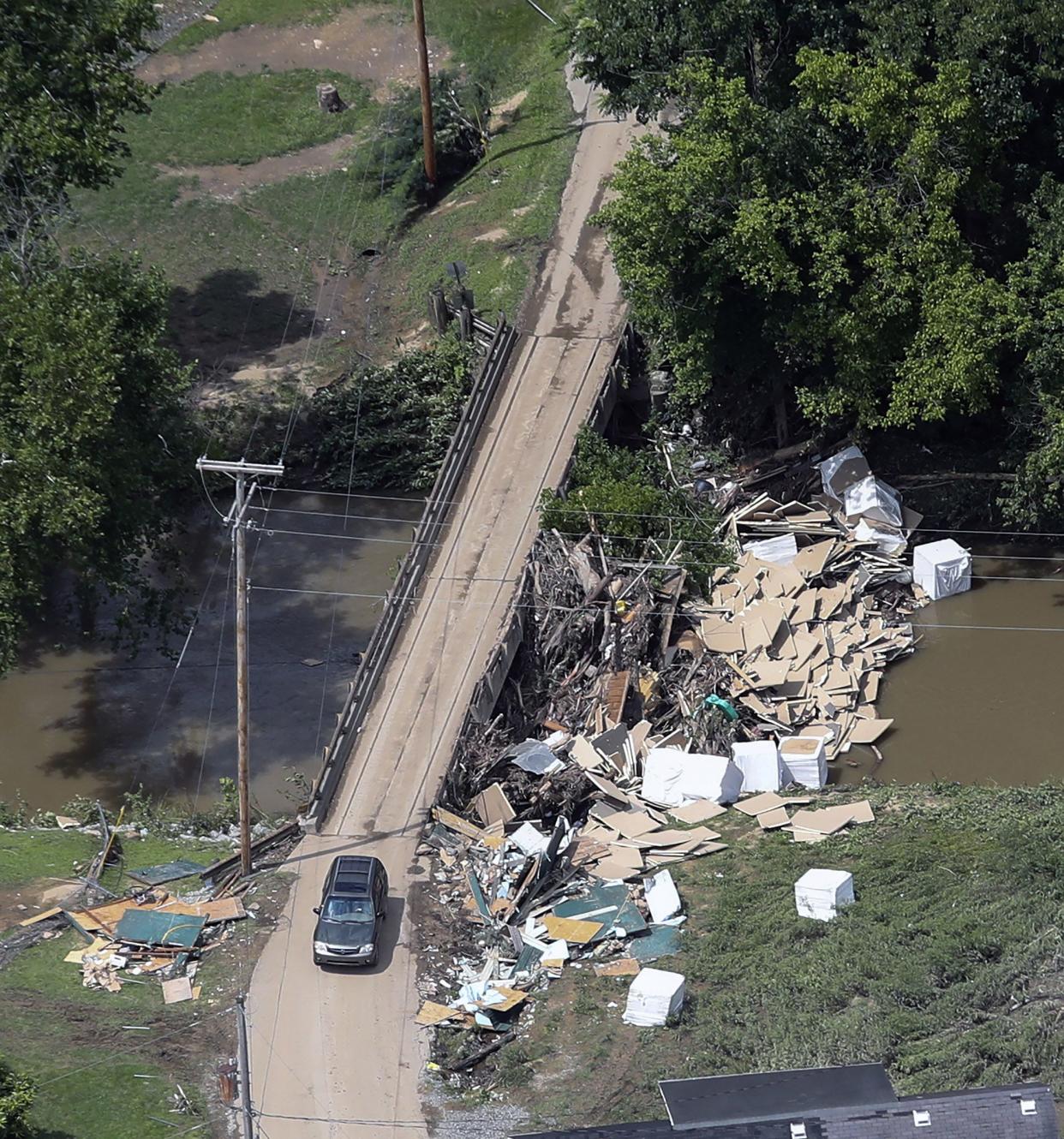 In this aerial image, a car drives over a bridge in Eastern Kentucky on Saturday, July 30, 2022, after historic rains flooded many areas of Kentucky, killing at least two dozen people.